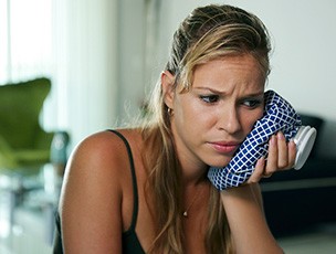 Woman holding ice pack to sore face