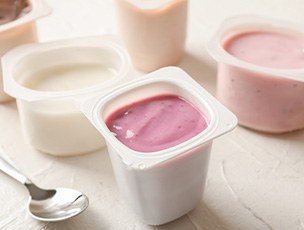 Spoon next to several plastic containers of pudding