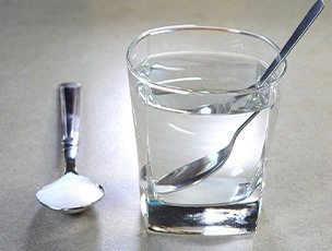 Glass of water with spoon next to spoonful of salt
