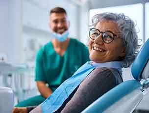 Woman with black glasses smiling in treatment chair