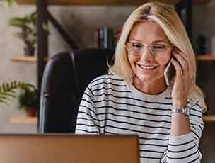 Woman with glasses smiling while talking on phone