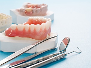 Set of lower dentures on a cast next to dental instruments