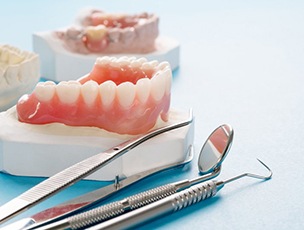a set of dentures next to dental tools