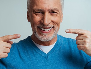 a man smiling and pointing at his dentures