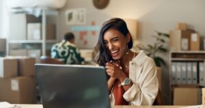 Woman looking at her laptop and smiling happily.